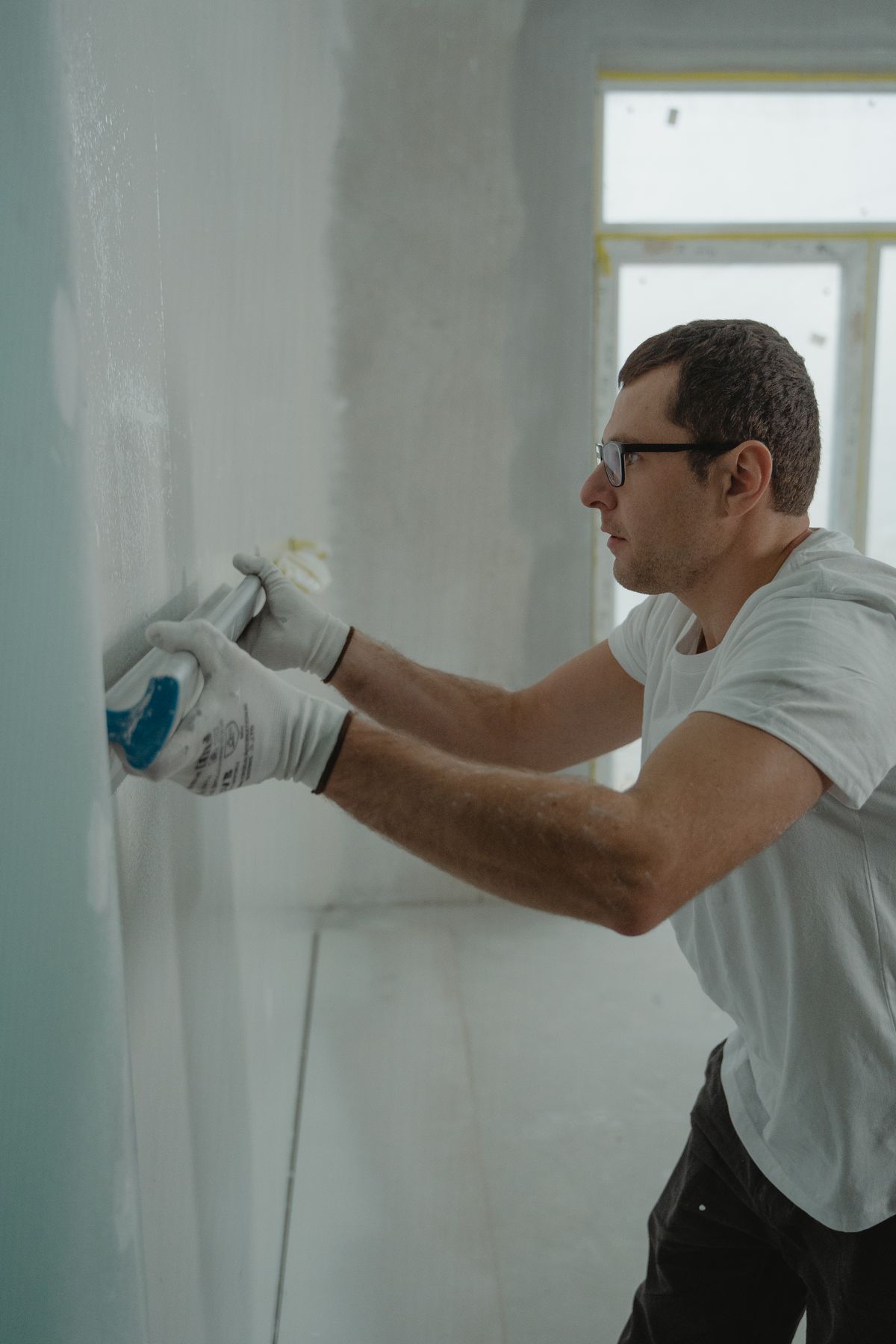 Worker applying finishing compound to a wall during interior repair